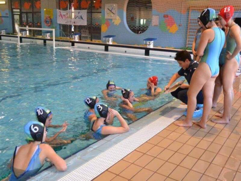Niños aprendiendo a nadar en una piscina infantil con instructor.