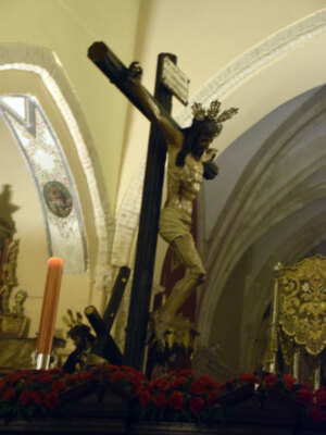 Crucifijo en iglesia con flores y velas.