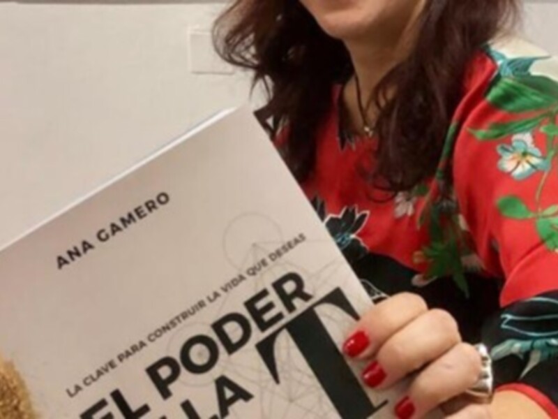 Una mujer sostiene un libro titulado "El Poder de la Vida" con una portada roja y verde, mostrando su dedo pulgar en un gesto de apertura.