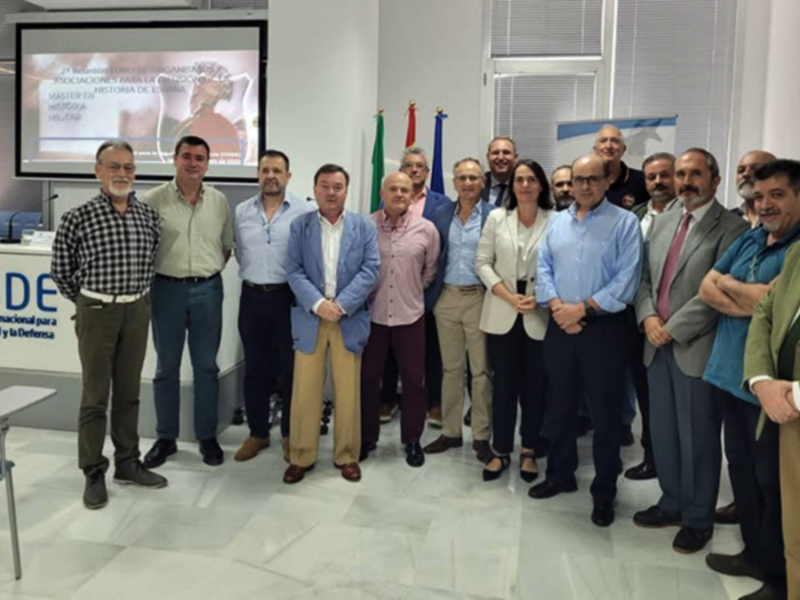 Grupo de personas posando en una sala con un panel de presentación en el fondo.