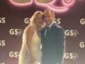 Un hombre y una mujer posan frente a un fondo con el logo de GS25, celebrando un evento especial.