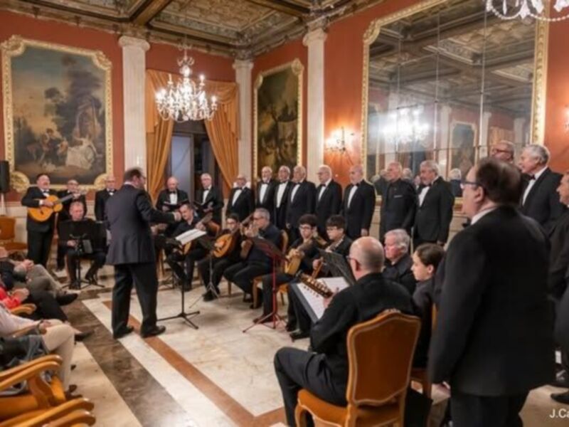 Un concierto de música clásica en un palacio, con músicos tocan instrumentos como violines y flautas. El público asiste sentado en sillas de madera, con un vestíbulo decorado y una gran espejo en el fondo. La iluminación es suave, con luces de araña y una lámpara en el techo.
