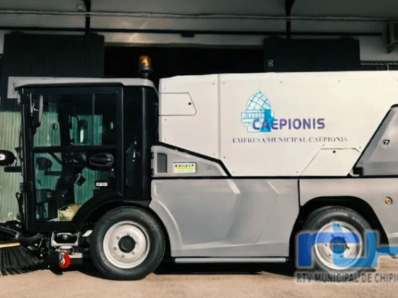 Un vehículo de limpieza municipal, probablemente una máquina de ruedas para calles. El vehículo está equipado con un sistema de limpieza avanzado, lo que indica su uso en áreas urbanas para mantener las calles libres de basura y suciedad. La marca visible sugiere que es parte del servicio municipal de Chipiona, una localidad en la provincia de Cádiz, España.