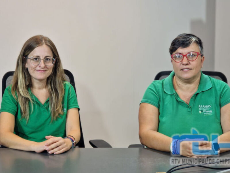 Dos personas en una reunión, ambas con camisetas verdes y gafas. La imagen es de una transmisión en vivo de la Municipalidad de Chipiona, con el logo visible.