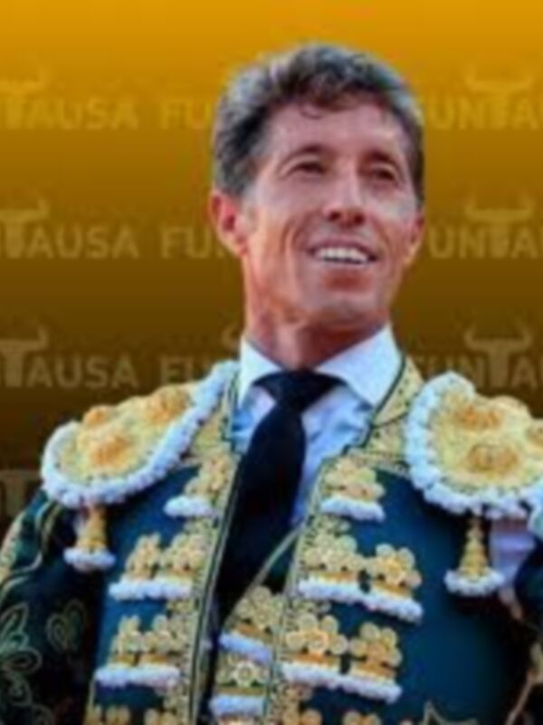 Un torero con un traje de lujo y flores en el cuello, posando para una foto.