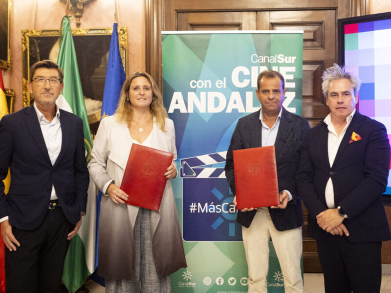 Una imagen de cuatro personas posando frente a una bandera española y un cartel que dice "Con el CINE Sur". El texto en la imagen es "#MásCanalSur".