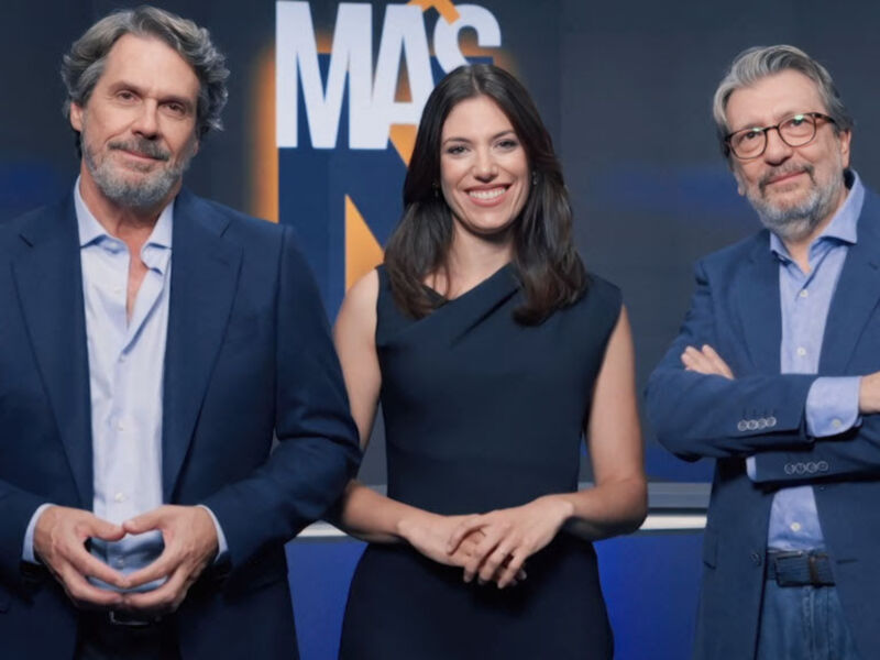 Tres personas posan frente a un fondo azul con la palabra "MAS" en el centro. La imagen parece ser de una transmisión televisiva o un programa informativo.