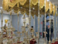 Un espectacular candelabro dorado con detalles elaborados, rodeado de mantas rojas en un entorno interior.