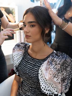 Una modelo, en maquillaje en el backstage abierto al público.